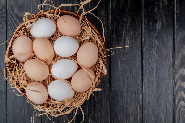 Top view of fresh chicken eggs on nest on a wooden background with copy space