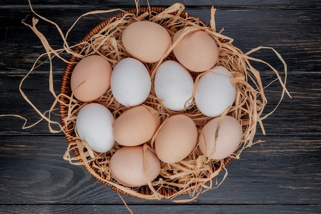 Top view of fresh chicken eggs on nest on a wooden background