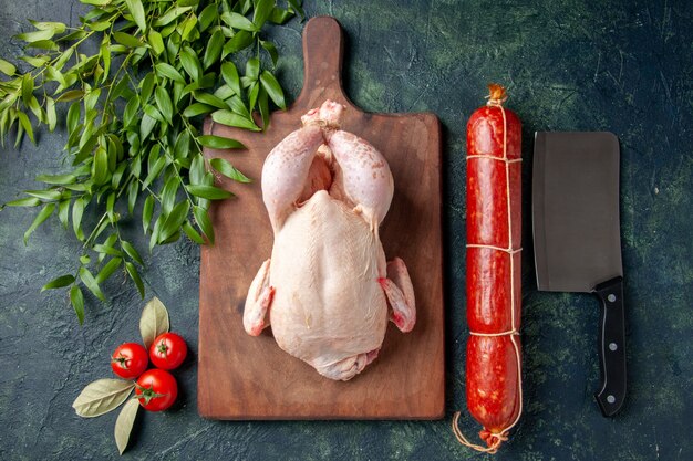 Top view fresh chicken with green leaves on dark-blue surface