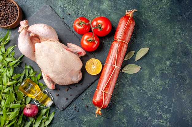 Top view fresh chicken with tomatoes and sausage on dark surface