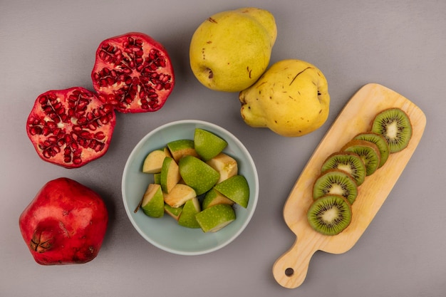 석류와 quinces 고립 된 나무 주방 보드에 키위 조각 그릇에 신선한 다진 사과 조각의 상위 뷰