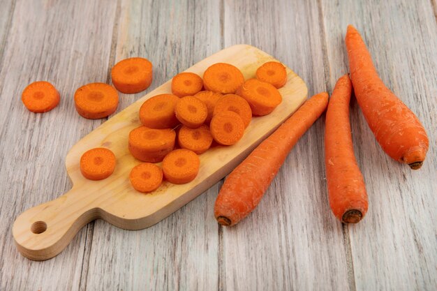 Top view of fresh chopped carrots on a wooden kitchen board with carrots isolated on a grey wooden background