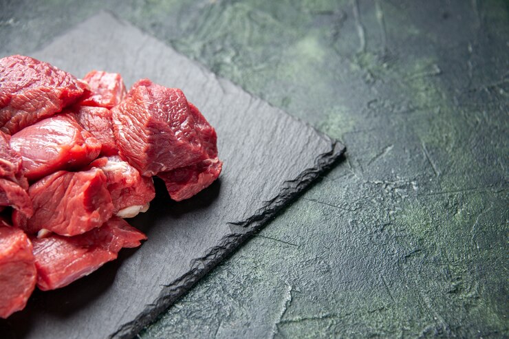Free Photo top view of fresh chopped raw beef steak on black board on the right side on green black mixed colors background