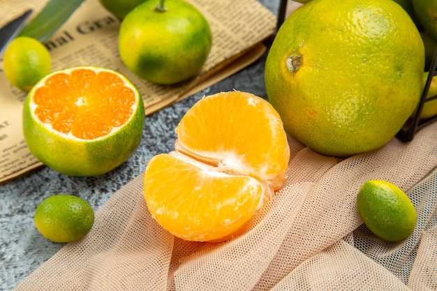 Top view of fresh citrus fruits cut in half forms and knife on newspaper on gray background