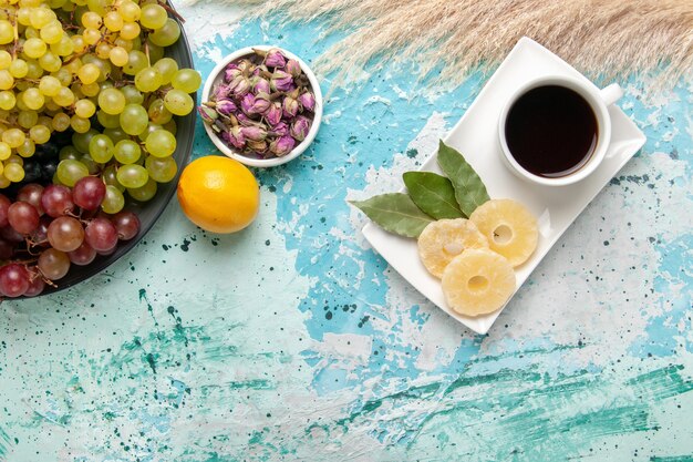 Top view fresh colored grapes with cup of tea on light-blue background fruits cookie sugar sweet cake bake pie