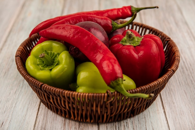 Free photo top view of fresh colorful bell and chili peppers on a bucket on a grey wooden wall