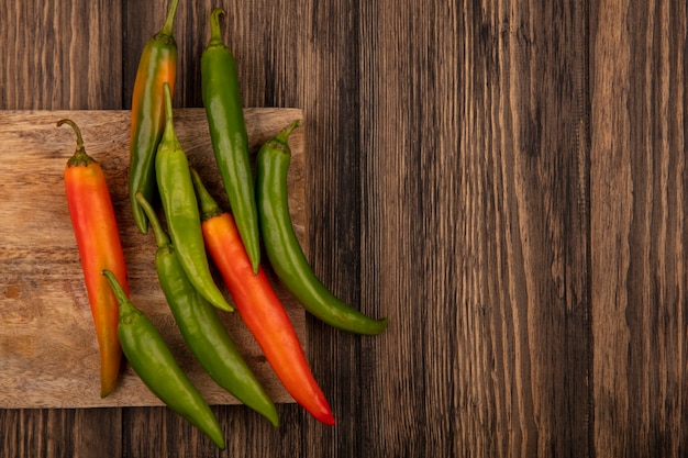 Top view of fresh colorful peppers isolated on a wooden kitchen board on a wooden background with copy space