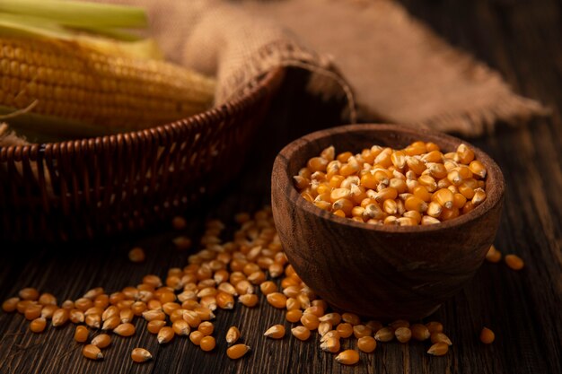 Вид сверху свежих зерен кукурузы на деревянной миске с зернами, изолированными на деревянной стене