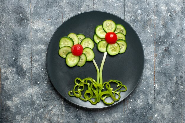 Top view fresh cucumbers flower designed salad on grey space