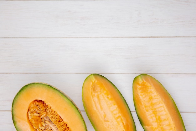 Top view of fresh and delicious cantaloupe melon slices on white wood with copy space