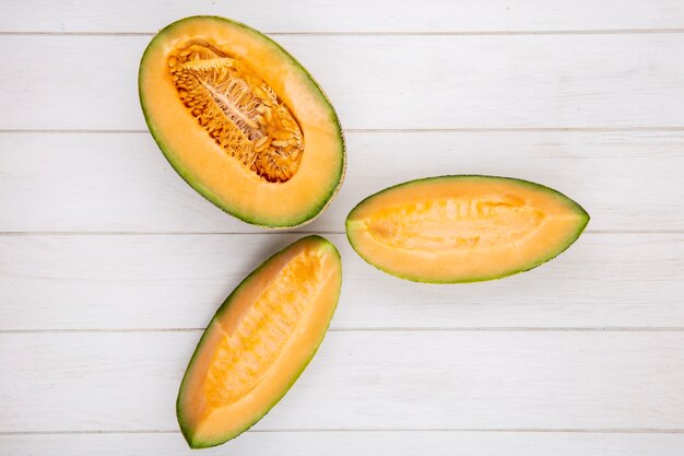 Top view of fresh and delicious cantaloupe melon slices on white wood