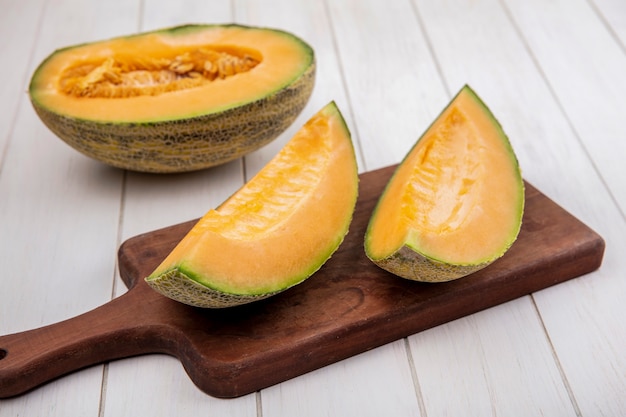 Top view fresh and delicious cantaloupe melon slices on wooden kitchen board on white wood