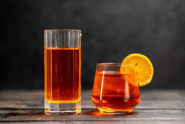 Top view of fresh delicious juice in two glasses with orange lime on dark background