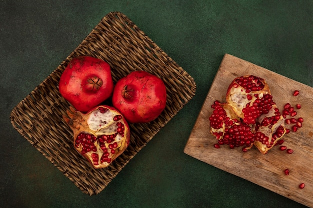 Top view of fresh and delicious pomegranates on a wicker tray with halved pomegranates on a wooden kitchen board