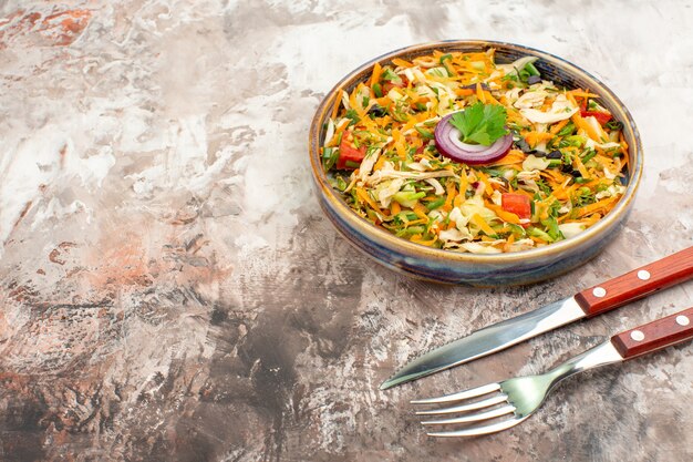 Вид сверху на свежий вкусный веганский салат из различных органических овощей с ножом и вилкой