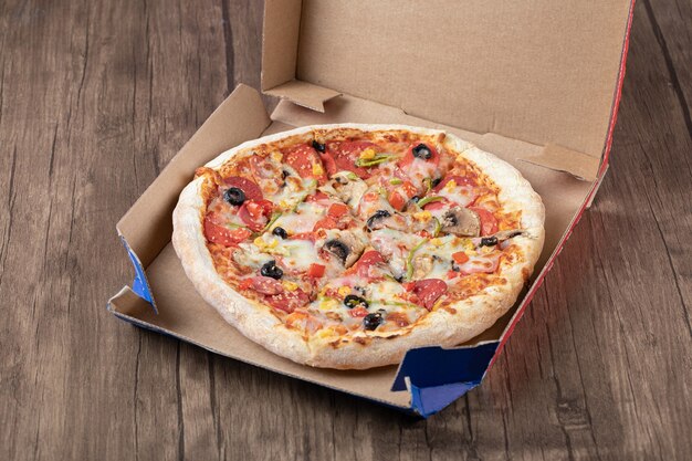 Top view of fresh delicious whole pizza on pizza box. 