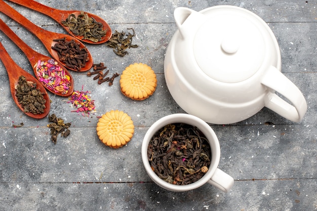 Free photo top view fresh dried tea with cookies and kettle on grey rustic desk