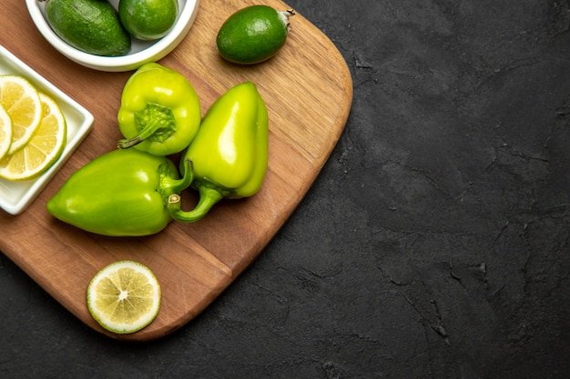 Top view fresh feijoa with green bell-pepper and lemon on dark surface fruits citrus plant meal