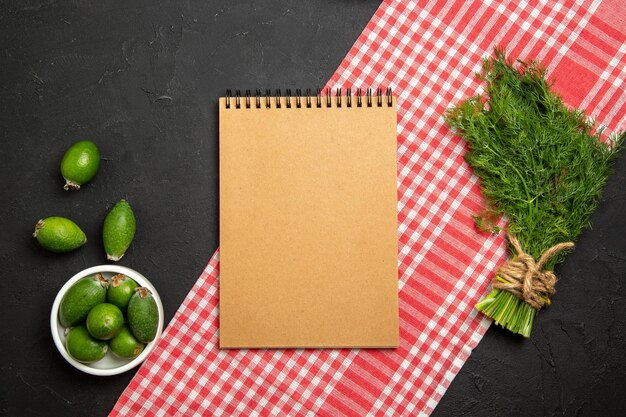 Top view fresh feijoa with greens and notepad on dark surface fruit green fresh green