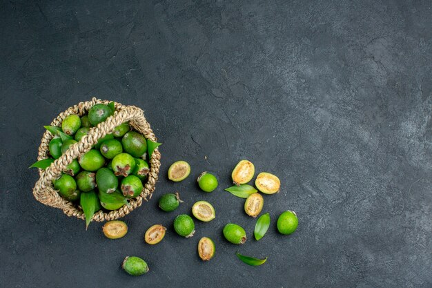 Top view fresh feijoas in basket on dark surface free space