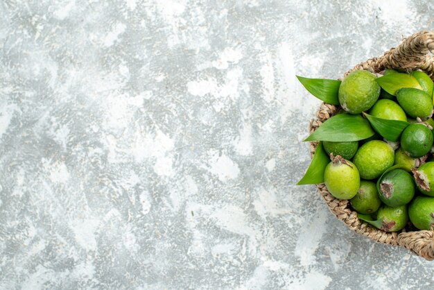 Top view fresh feijoas in wicker basket on grey isolated surface free place