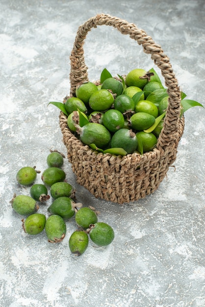 Top view fresh feijoas in wicker basket on grey isolated surface