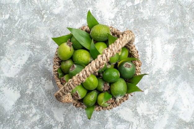 Top view fresh feijoas in wicker basket on grey isolated surface