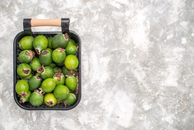 Top view fresh feykhoas in basket on grey surface with copy place