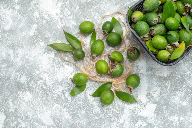 Top view fresh feykhoas in basket on grey surface with free space