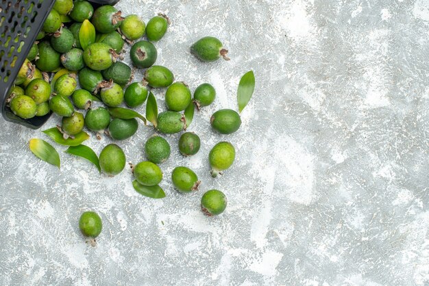 Top view fresh feykhoas scattered from basket on grey surface copy space