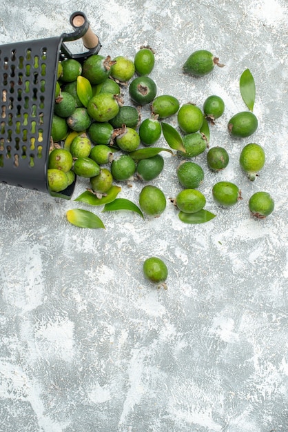 Top view fresh feykhoas scattered from basket on grey surface