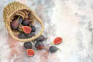 Free photo top view fresh figs scattered from wicker basket on nude background