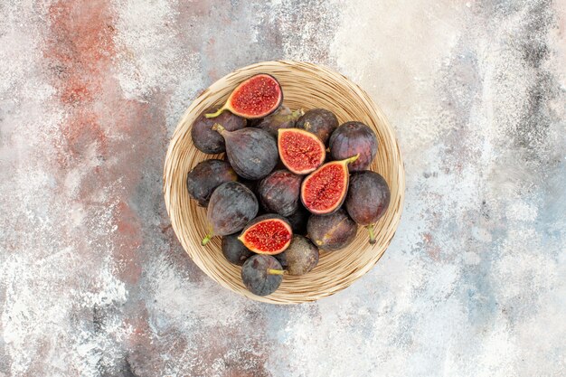 Top view fresh figs in wicker basket on nude background