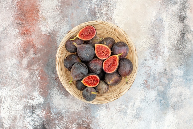 Top view fresh figs in wicker basket on nude background