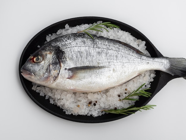 Top view fresh fish in pan with herbs