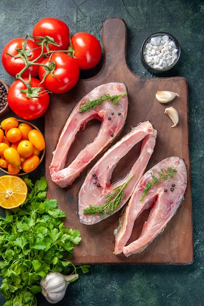 Foto gratuita vista dall'alto fette di pesce fresco con verdure e kumquat su sfondo scuro