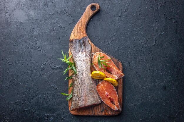 Вид сверху ломтики свежей рыбы с лимоном на темном фоне цветное фото мясо еда океан вода здоровье ужин еда