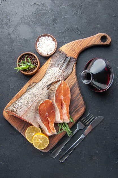 Вид сверху ломтики свежей рыбы с лимоном и флягой вина на темном фоне морепродукты мясо цвет вода еда здоровье океан еда
