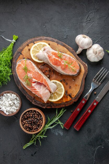 Foto gratuita fette di pesce fresco vista dall'alto con limone e aglio sul tavolo scuro