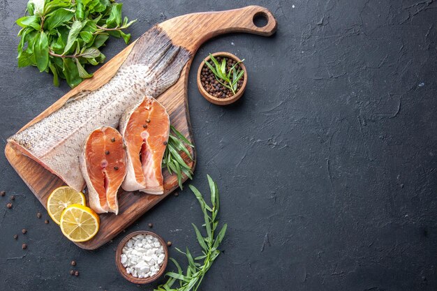 Top view fresh fish slices with lemon and greens on dark background seafood health meat dinner ocean meal restaurant food