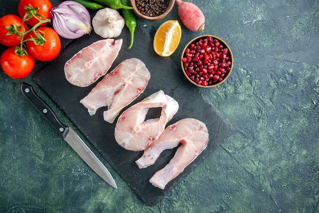 Top view fresh fish slices with red tomatoes on dark blue background ocean meat seafood pepper dish food sea meal water