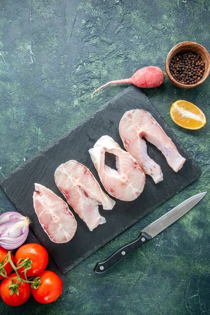 Top view fresh fish slices with red tomatoes on a dark blue table ocean meat seafood food pepper water dish sea meal