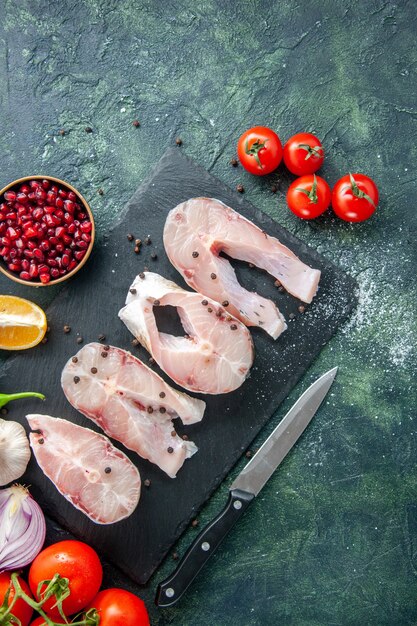 어두운 파란색 테이블에 빨간 토마토와 상위 뷰 신선한 생선 조각 바다 고기 해산물 후추 요리 바다 식사 물 음식