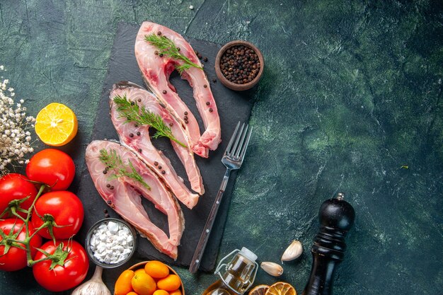 top view fresh fish slices with red tomatoes and kumquats on dark background