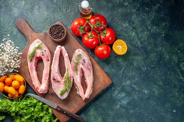 top view fresh fish slices with tomatoes and greens on dark background