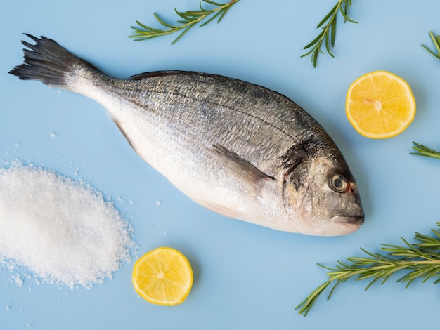 Vista dall'alto pesce fresco con limone ed erbe aromatiche