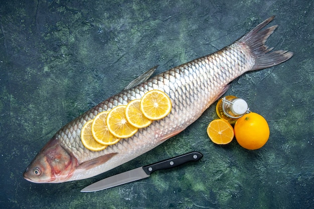 Вид сверху свежей рыбы с ломтиками лимона, ножом, лимоном на кухонном столе, свободное место