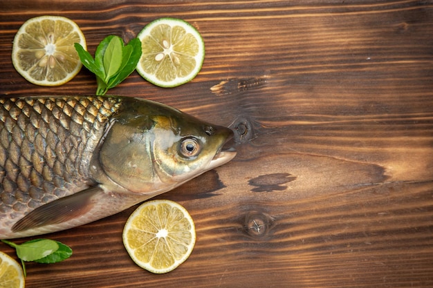 Free photo top view fresh fish with lemon slices on a wooden desk