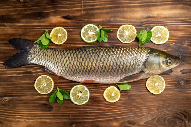 Top view fresh fish with lemon slices on wooden desk