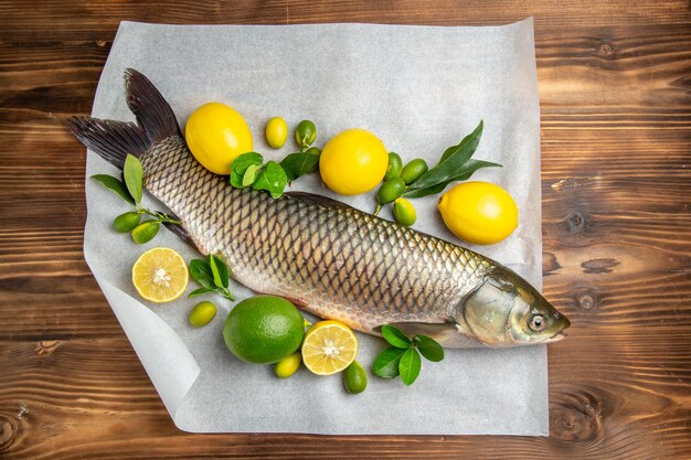 Top view fresh fish with lemons on a brown desk